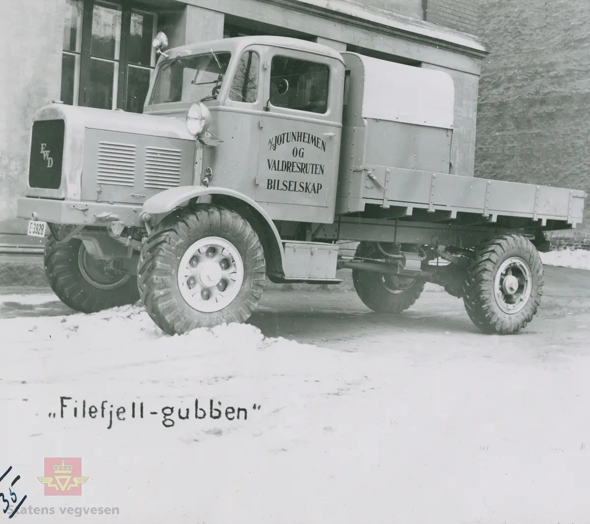 Tekst på bildet "Filefjell-Gubben". FWD lastebil modell SU fra A/S Jotunheimen og Valdresruten Bilselskap (JVB) med kjennetegn E-3928. Bilen ble levert til Jotunheimen, Valdresruten i 1936, og holdt vegen over Filefjell åpen. Klikk på pilen til høyre for å se tilleggsbilder: Legg merke til benkene på lasteplanet med tak og presenning til ly for vær og vind for brøytemannskap.   
Etter en tøff vinter 1936-1937 mottok Colbjørnsen brev fra JVB, A/S Jotunheimen og Valdresruten Bilselskap  30.04.1937, hvor de sier seg meget fornøyd med bilen de kjøpte før jul i 1936. Jf. boka "Familiefirmaet-utenom allfarvei/2000 Årsboken."Colbjørnsen & Co A/S, av Bjørn Ausjen Johannessen. Bilde av "Filefjell-Gubben" i A/S Jotunheimen og Valdresruten Bilselskap  på en av veivesenets garasjer på Filefjell vises i tilleggbildene.  FWD lastebilen "Filefjell-Gubben" ble innkjøpt av JVB  i 1936. Den til da kraftigste i landet. Vegfolk kom da også fra fjern og nær for å bivåne brøytingen, og for å se og lære. 
 "A/S Jotunheimen og Valdresruten Bilselskap  ble etablert i 1919 og har vært selve livsnerven gjennom Valdresbygdene. "Filefjell-Gubben" ble satt inn i arbeidet med å holde Filefjellvegen oppe. Med felles innsats og arbeid fra Staten og selskapets side, lykkes det å holde Filefjellvegen farbar for vintertrafikk vinteren 1936-1937, den første fjellovergang i Norge som var åpen året rundt." Jf. Kilde: "JVB. Den spede begynnelse-A/S Jotunheimen og Valdresruten Bilselskap."  
Personene på bildet er ukjente. Bildene som vises er både fra Oslo og Filefjell. 
Bildene er registrert enkeltvis på nr: 
Bilde 2) NVM 00-F-33671
Bilde 3  NVM 00-F-33672
Bilde 4  NVM 00-F-33704
Bilde 5) NVM 00-F-33705
Bilde 6) NVM 00-F-33707
Bilde 7) NVM 00-F-33708
Bilde 8) NVM 00-F-33710
Bilde 9) NVM 00-F-33711
Bilde 10)NVM 00-F33659
Bilde 11)NVM 00-F33660