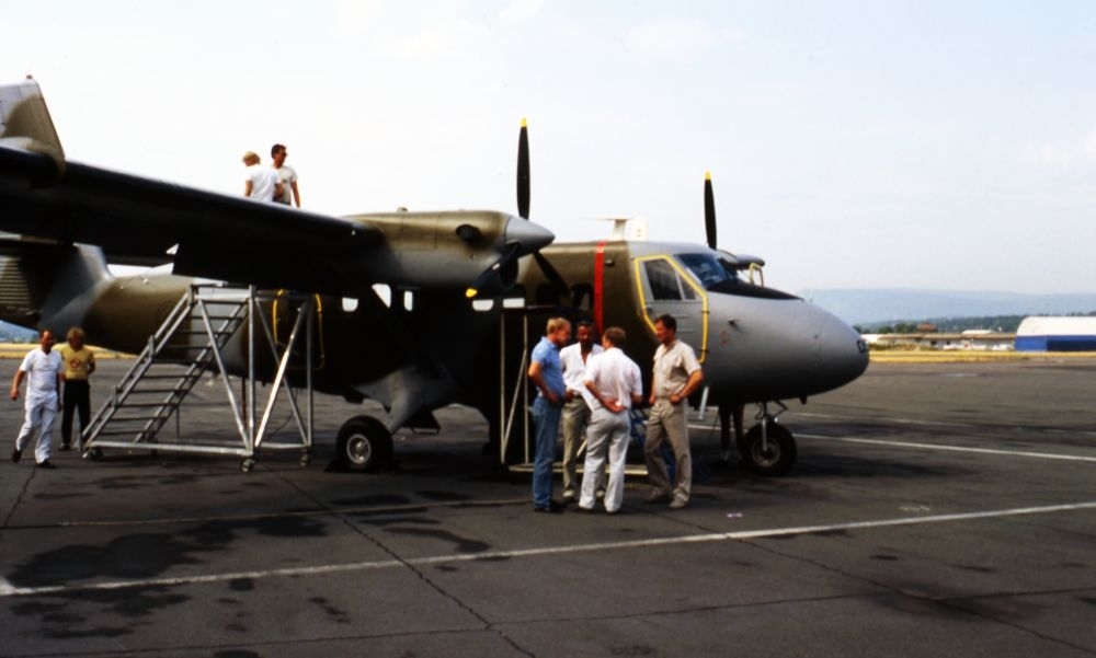 Lufthavn/Flyplass. Et fly, DHC-6 Twin Otter, serienummer 67-057, type 100, fra 719 skvadronen. Fire personer samlet ved flyet. To personer har tatt plass på toppen av flyet.