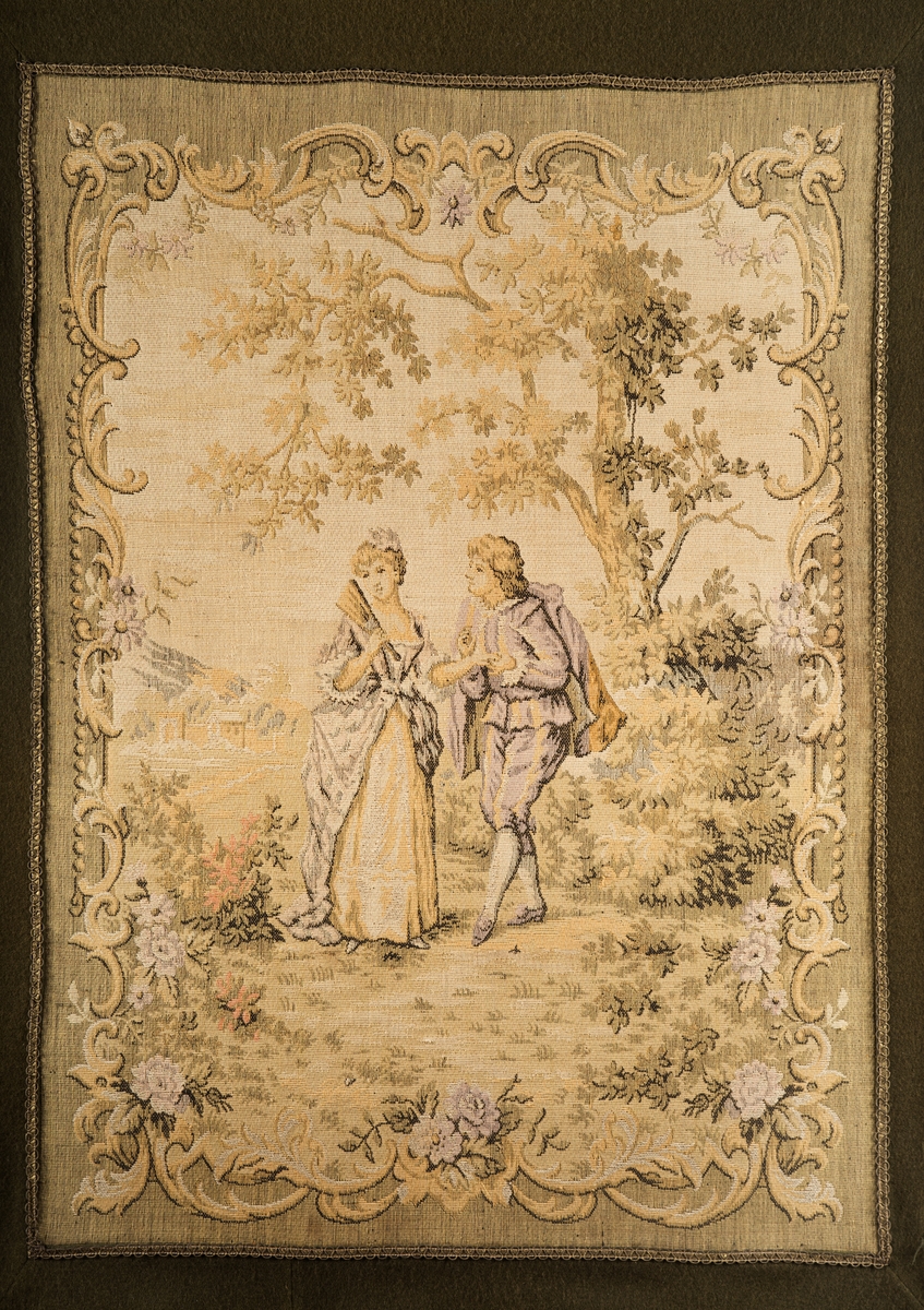 Kvadrisk motiv med mann og kvinne i et landskap med et tre og annen vegetasjon. Motivet er omrammet av rocaille-ornamenter og blomster.