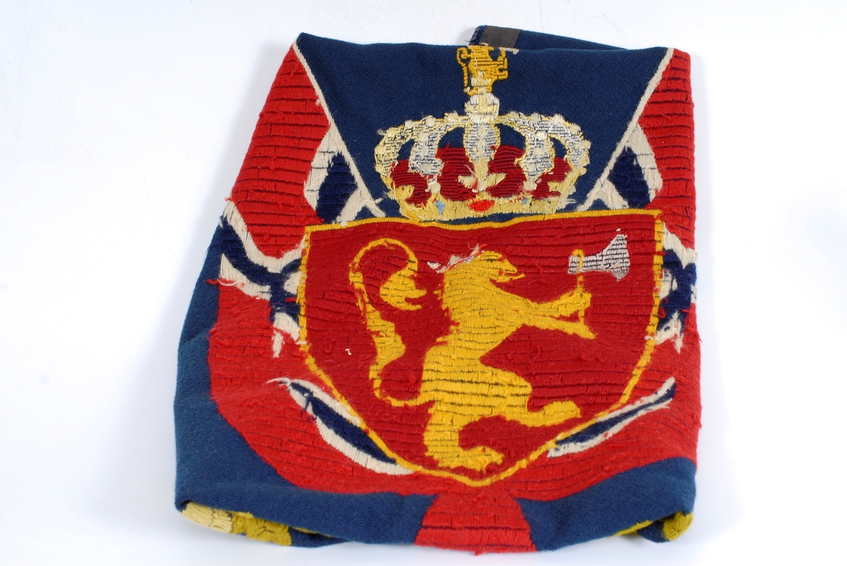 det kongelig norske riksvåpen med et flagg på hver side og eikeblader