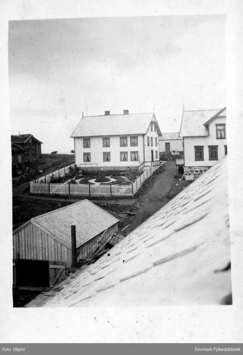 Dette bildet er tatt en gang før 1944 og viser disponentboligen i Øksfjord. På huset kan man se vinduer med gardiner i. På taket kan man se to skorsteiner. Huset har en stor hage som er omringet av et gjerde. Huset har også en grunnmur.