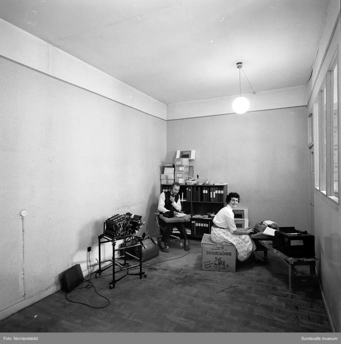Provisoriskt kontor på Sjögatan 3, med en man och en kvinna som försöker jobba utan möbler. Rockwool.
