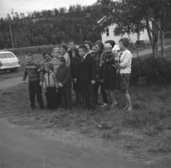 Noen kvinner og barn/ungdommer har stilt opp langs en grusve