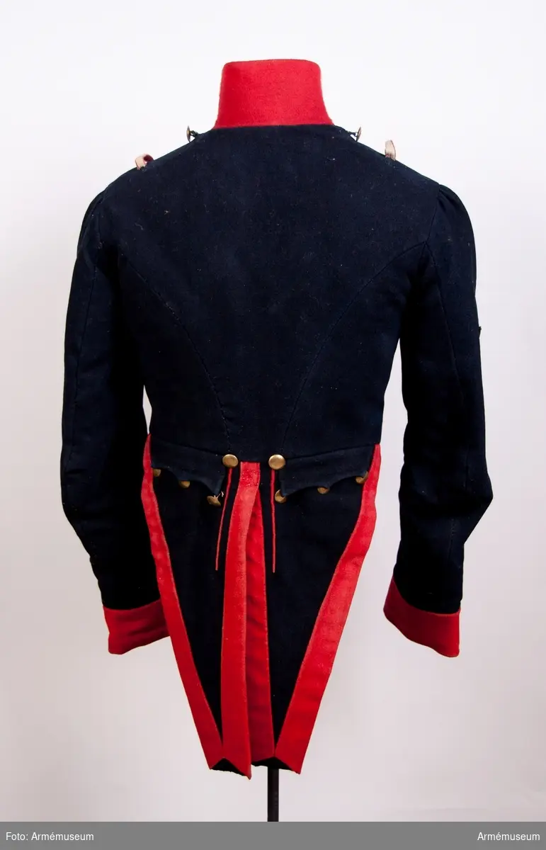 Grupp C I.
Frack av mörkblått kläde med röd krage, ärmuppslag och bröstrevär.