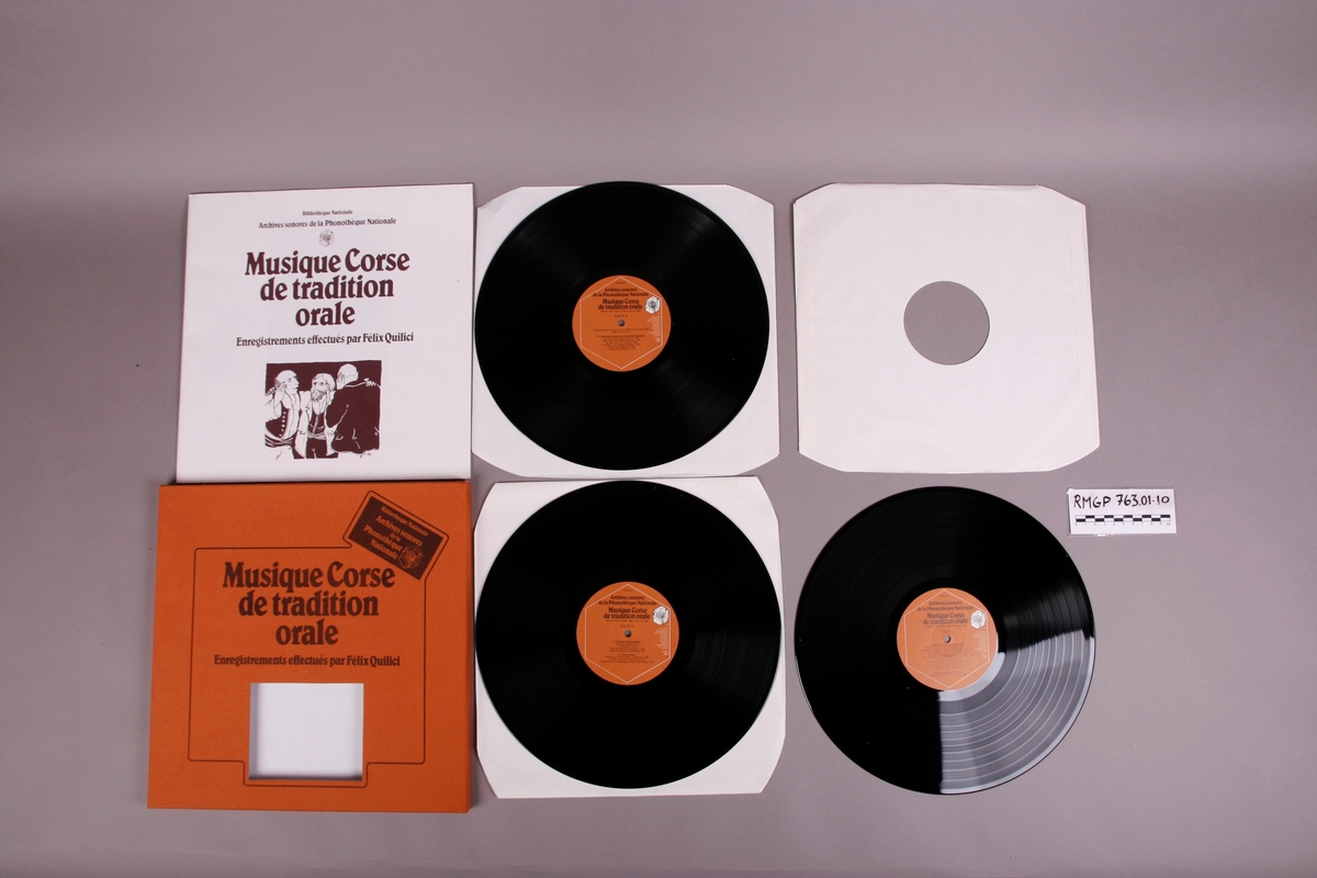 Plateomslag i form av en eske i oransje stoff, tre grammofonplater i svart vinyl som ligger i papirlommer, samt et hefte. I tillegg et klistremerke inne i  esken.