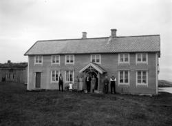 Foto fra et våningshus, med en familie/slekt stående samlet 