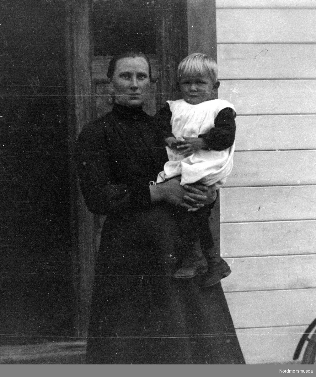 Foto av en kvinne med et lite barn på armen. De har trolig en relasjon til Sverdrupfamilien, eventuelt fra deres bekjentskaper. Bildet er sannsynligvis tatt i Møre og Romsdal fylke omkring 1910 til 1930. Fra Nordmøre museums fotosamlinger.  /Reg:EFR2013/
