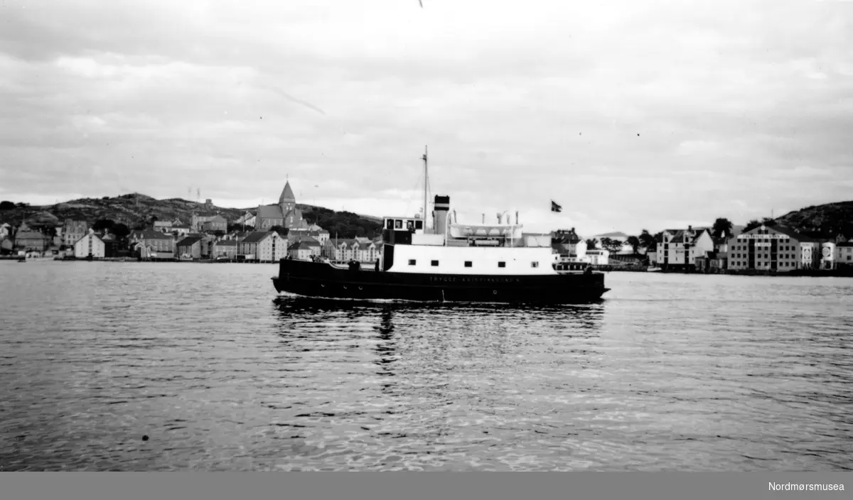 På bildet ser vi B/F”Trygge”, Storviks mek. verksteds bnr. 11 i 1938 på havna i Kristiansund.
B/F”Trygge” ble bygd for statlige midler i 1937-38 og var klinkbygget i stål. 
Ferga hadde følgende hovedimensjoner: L 93`2” x B 25`0” x D 10`6”. Dette var den første bilferga som var bygd i stål i Møre og Romsdal. Ferga hadde en tonnasje på 137 bruttoregistertonn og var utstyrt med en Wichmann 300 BHK 2-takts 4-sylindret råoljemotor som ga ferga en fart på 10 knop. Den hadde en kapasitet på 14 personbiler og sertifikat for 260 passasjerer. Den ble leid av MRF og satt inn i ruten Kristiansund—Bremsnes, Kristvika, Kvernes, Gjemnes, og Torvikbukt. 
Under krigen gikk den fra Torvika kl.08.00 og var i Kristiansund ca. kl. 10.00. Retur fra Kristiansund kl.16.00 og kom til Torvika ca. kl.18.00.
Det var 4-5 tyske vakter om bord i tidsrommet 1940-45.
Bilene måtte rygge om bord den gangen.
I 1966 ble den solgt til et partsrederi ved Ingvald S. Vestre, Vestrefjord. Ferga ble ombygd og ominnredet og blant annet ble det store overbygget fjernet og erstattet av casing og styrhus på styrbord side. Det ble også innsatt ny Callesen hovedmotor på 460 BHK og den fikk navnet ”Vestra” og ble utleid til MRF for trafikk i det forlengede fergesambandet på Hjørundfjorden, der den gikk frem til 1982.
MRF leide ferga til etter at den ble solgt til et firma for transport av annleggsutstyr. Også etter dette skal den være brukt som bilferge. 
Bildet er fra 1940-tallet.s bnr. 11 i 1938 på havna i Kristiansund.
B/F”Trygge” ble bygd for statlige midler i 1937-38 og var klinkbygget i stål. 
Ferga hadde følgende hovedimensjoner: L 93`2” x B 25`0” x D 10`6”. Dette var den første bilferga som var bygd i stål i Møre og Romsdal. Ferga hadde en tonnasje på 137 bruttoregistertonn og var utstyrt med en Wichmann 300 BHK 2-takts 4-sylindret råoljemotor som ga ferga en fart på 10 knop. Den hadde en kapasitet på 14 personbiler og sertifikat for 260 passasjerer. Den ble leid av MRF og satt inn i ruten Kristiansund—Bremsnes, Kristvika, Kvernes, Gjemnes, og Torvikbukt. 
Under krigen gikk den fra Torvika kl.08.00 og var i Kristiansund ca. kl. 10.00. Retur fra Kristiansund kl.16.00 og kom til Torvika ca. kl.18.00.
Det var 4-5 tyske vakter om bord i tidsrommet 1940-45.
Bilene måtte rygge om bord den gangen.
I 1966 ble den solgt til et partsrederi ved Ingvald S. Vestre, Vestrefjord. Ferga ble ombygd og ominnredet og blant annet ble det store overbygget fjernet og erstattet av casing og styrhus på styrbord side. Det ble også innsatt ny Callesen hovedmotor på 460 BHK og den fikk navnet ”Vestra” og ble utleid til MRF for trafikk i det forlengede fergesambandet på Hjørundfjorden, der den gikk frem til 1982.
MRF leide ferga til etter at den ble solgt til et firma for transport av annleggsutstyr. Også etter dette skal den være brukt som bilferge. 
Bildet er fra 1938. (Info: Peter Storvik) --
 havna i Kristiansund. I bakgrunnen kan vi se Nordlandet. Fra Nordmøre museums fotosamlinger.