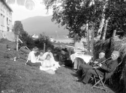 Foto av en gruppe mennesker sittende nedenfor et bolighus; t