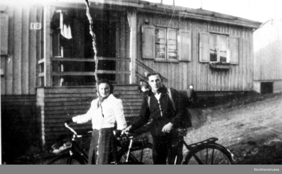 Ungt par med ryggsekk skal på sykkeltur. En søndag ca 1947, brakke nr 10, Kristiansund.  Fra Nordmøre Museum sin fotosamling.