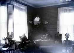 Foto av to kvinner og en mann sittende i ei stue/salong, rik