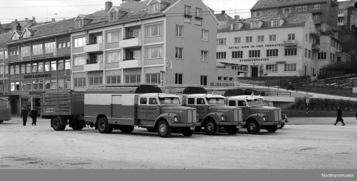 Frei billags godsruter 1960. Torkil Øyen 2011: Bilene på bildet er
tre stk Scania-Vabis L75-54 1959 modeller, levert til KFB den 01.03.1960. De ble da satt inn på den nystartede person/godsruta til Åndalsnes. Regnr var T-6102, T-6103 og T-6104, den siste er restaurert og står 2011 på Stortua, det gjør også en av de to andre da denne ble ombygd til kranvogn/bergingsbil i 1971/72 og omreg til UX 12679 den 25.03.72.

Hengeren på bildet er en Maur 60A 1960 mod med regnr T-6108 som kunne være kjekk å ha ved store godsmengder..

Fra Nordmøre Museums fotosamlinger.



