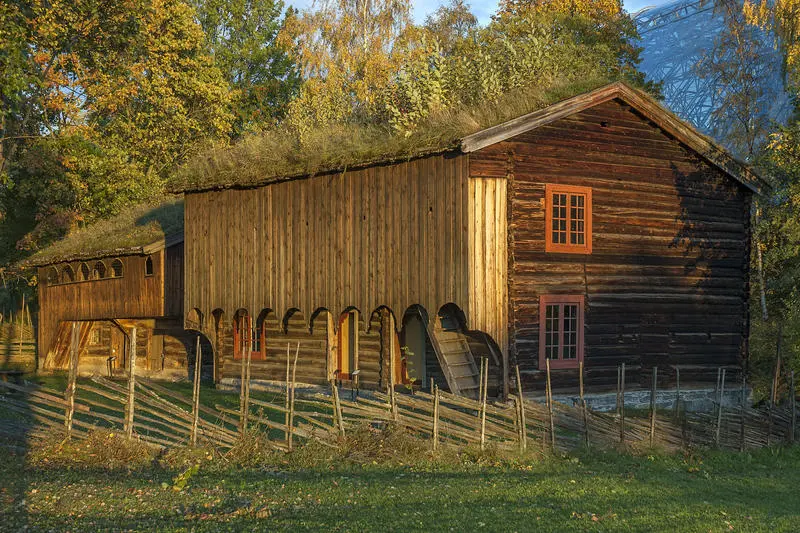 Grimsrudbygningen på Hedmarkstunet er en brunlig toetasjers tømmerbygning med to rutete vinduer over hverandre i gavleveggen og tettet svalgang i andre etasje.