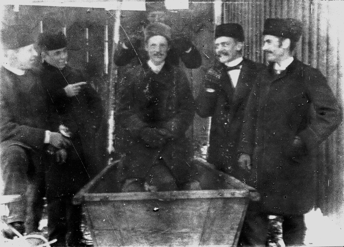 En man sitter i ett badkar, fem män står bredvid. Fotograf Alfred Bergendahl. Givare H Bergendahl.