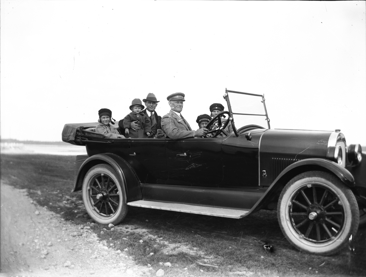 Familjen Brundin i bil, med chaufför. Innan familjen skaffade bil hyrdes en bil av en chaufför som hette Anger. På bilden syns han vid ratten, David Brundin sitter i baksätet som omväxling. Bilen en Oldsmobile fråm omkring 1923.