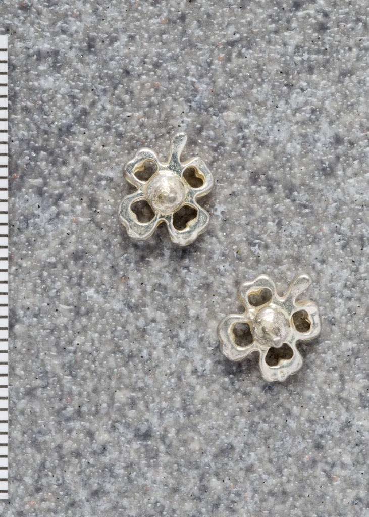 Ørepynt/øredobber, 2 stk. Formet som små firkløver med diamantlignenede sten i midten. Mangler festeanordning.
