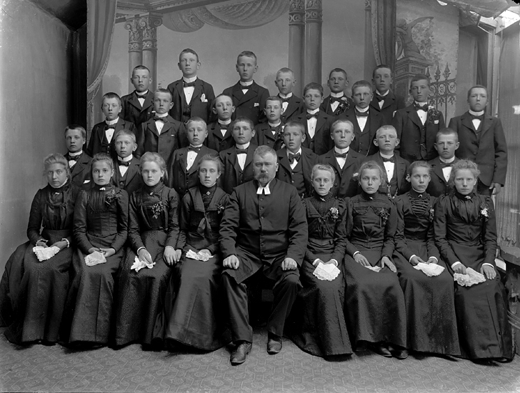 Konfirmationsklass med prästen i mitten. Ateljéfoto, ca. 1900.
