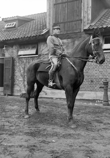 Foto av man i uniform till häst, utanför ett stall.
I 11, Växjö