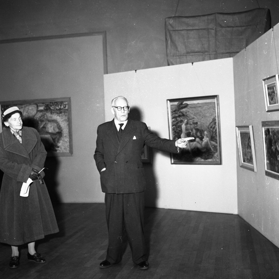 SM utställning Edward Hald. 1957.03.
Glaskonstnären Edward Hald förklarar något för besökare.