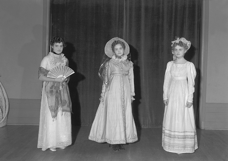 Tre kvinnor i klänningar m.m. från början av 1800-talet.