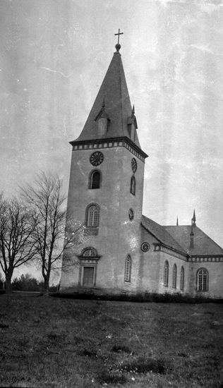 Foto på en kyrka med två träd utanför.