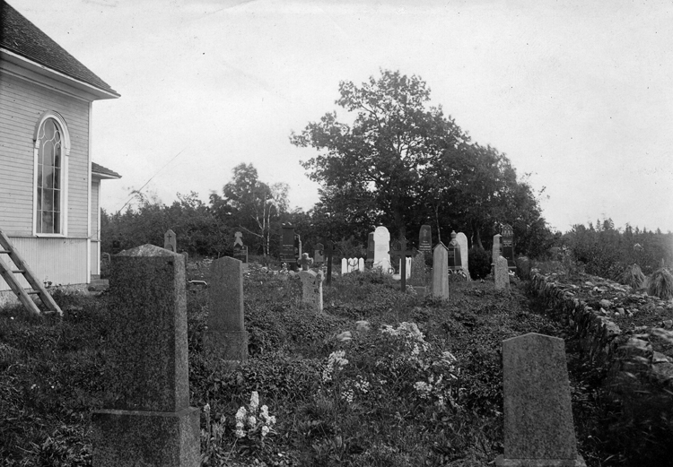 Foto på en kyrka som syns lite vid sidan och en massa gravstenar utanför.