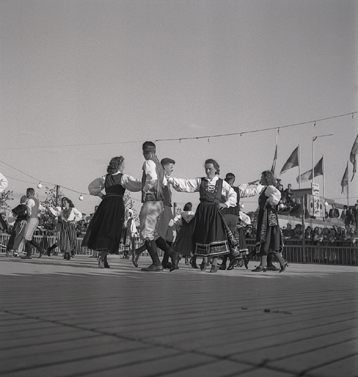 Jubileumsutställning. 
Folkdansuppvisning. Ett folkdanslag i Värendsdräkt m.m. visar upp
sig på en dansbana.