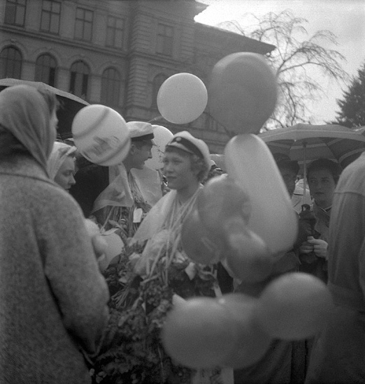 Studenterna första dagen, 12/5 1958. 
En kvinnlig student gratuleras på skolgården till dåv. Växjö Högre
Allmänna läroverk. 
Något suddigt foto.