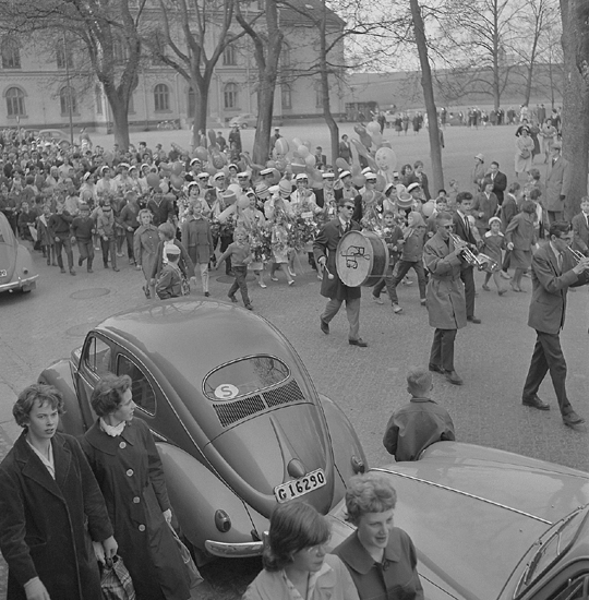 Studenterna, första d. 1960. 
Studenterna tågar längs Skolgatan, mot Linnéparken och talet vid Esaias Tegnérs staty. 
I bakgrunden syns Norrtullskolan.