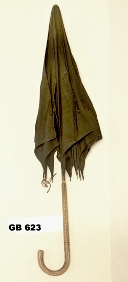 Svart paraply.
Mått: Diagonalt, utspänd 1,16 m. Käpp 0,85 m lång.
Paraplykäpp i trä med böjt och utskuret handtag.
Utspänningsanordning i svart metall.
Inskrivet i huvudkatalogen 1996-1997.