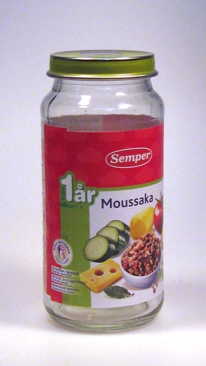 Barnmatburk.
Ofärgat glas, grönt plåtlock, röd/grön/vit etikett "Semper 1 år Moussaka".
Märkningen "L 07" betyder Limmared och att det är i form nr 07 som burken tillverkats i.
Funktion: Barnmatburk