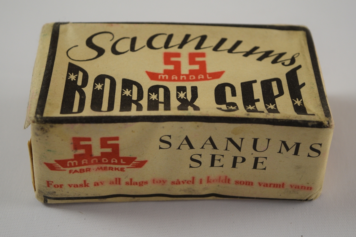 Rektangulær såpe, brun, tre like såper (A, B, C) innpakket i papir med trykk. Produsert på Saanums Sepefabrikk i Mandal. Rektangulær fordypning med relieffteksten "Borax" på overside og "Saanum" på underside.
