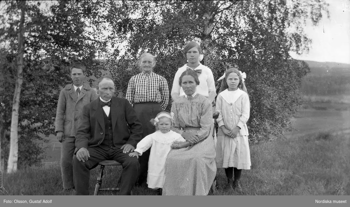 Gruppfoto av en familj med björkar i bakgrunden, början av 1900-talet. 