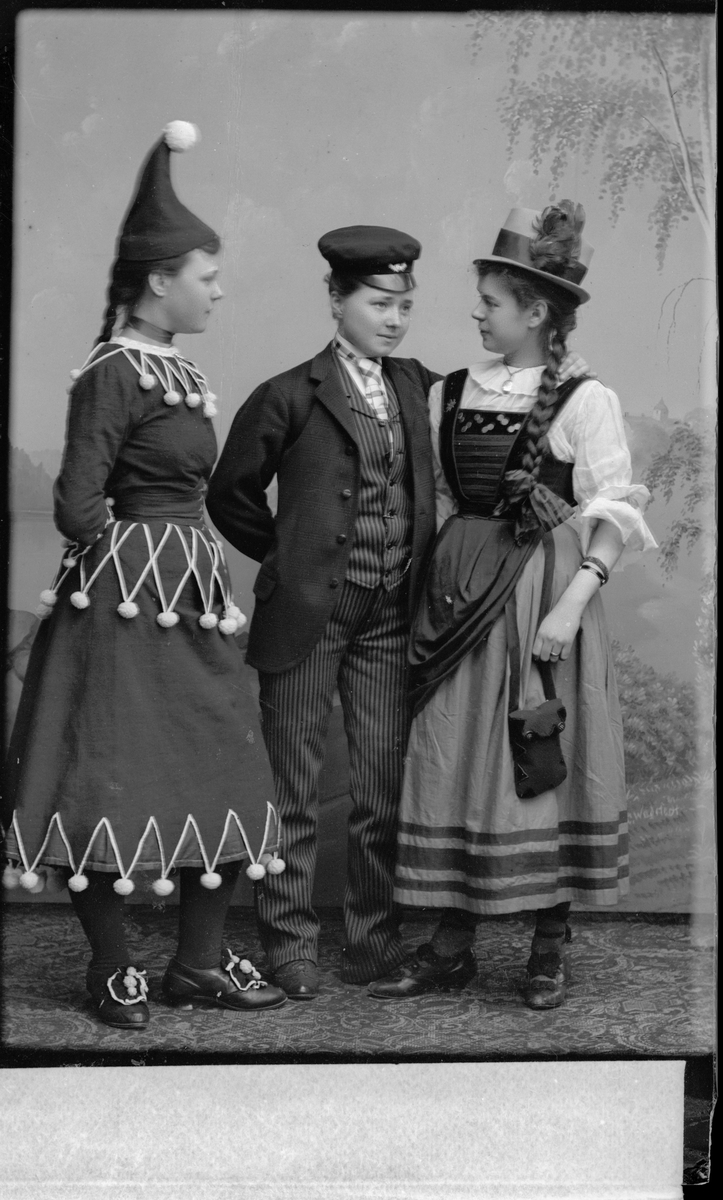 Två flickor och en pojke, klädda i folkdräkter.