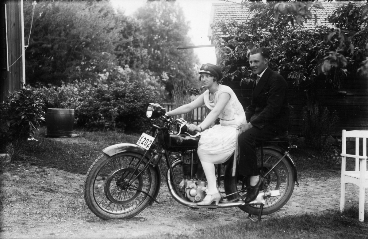 Bilden tagen i Målars trädgård. Motorcykeln är förmodligen en belgisk FN. Personerna är Margit Swanström från Lenninge och Petrus Olsson från Bollnäs. Foto 1929.