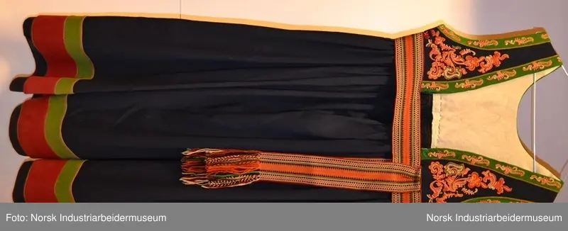 Livet er foret med et ubleket stoff. Livet er mørkt blått med grønn kanting. Både kantene og livet er prydet med plattsøm foran og bak. 
Nederst på stakken er det to border. Den øverste er  i grønt kantet med lilla og orange kontursting. Den nederste er i rødt kantet med gult. Nedenfor bordene ses den mørkeblå stakken. Den er kantet med rødt. 
Det brikkevevde beltet som hører til bunaden er sydd fast i kanten på livet. Borden i midten er orange og svart. På hver ytterside er det en rød, hvit og svart bord. Beltet har også striper i brunt, hvitt, rødt, svart og turkis. Beltet lukkes med hekter. Begge frynseendene på beltet er klipt av. Det ene frynesstykket er montert på beltet, slik at det alltid henger ned langs stakken i samme lengde. Det andre frynsestykket er løst og må festet på beltet med en sikkerhetsnæl eller liknende.