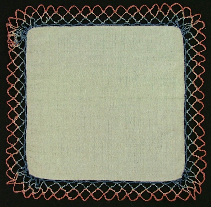Av gråvitt linne i spetskypert, kantad med 2,7 cm bred knypplad uddspets, nätformat helslag, blå och ljusröd. Smal fåll handsöm.
Karin Haglund sept 2006