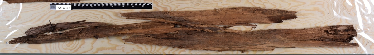 Deler av en rektangulær gravkiste. Det er kistebunnen, kistelokk, kistesidevegger og deler av hodeendegavlen.
Kistelokket er laget av et flatt og rektangulært bord som er laget av ett stykke tre. Bordet er sterkt fragmentert.
Kistesidene er i litt bedre tilstand. Bordene er avlange, rektangulære og laget av et stykke tre hver. Bordene ble festet med spiker til kistebunnen. Det er en spiker igjen i venstre sideveggen. Begge sidebordene har langsgående sprekker og er delvis brudd i flere deler.
Kistebunnen er laget av et flatt og rektangulært bord som er laget av ett stykke tre. Det er flere langsgående sprekker og flere kvisthull. Fargen er mørk brun med enkelte lysere brune partier i hodeenden.  I begge kortender er det rester etter hodegavlen og fotendegavlen og langs venstre siden er det rester etter kisteveggen. Hodeenden er bredere enn fotenden.
Hodeendegavlen er laget av en tykkere rektangulær trekube. Den har brudd opp i flere deler både på grunnen av nedbrytingen og under utgravningen.