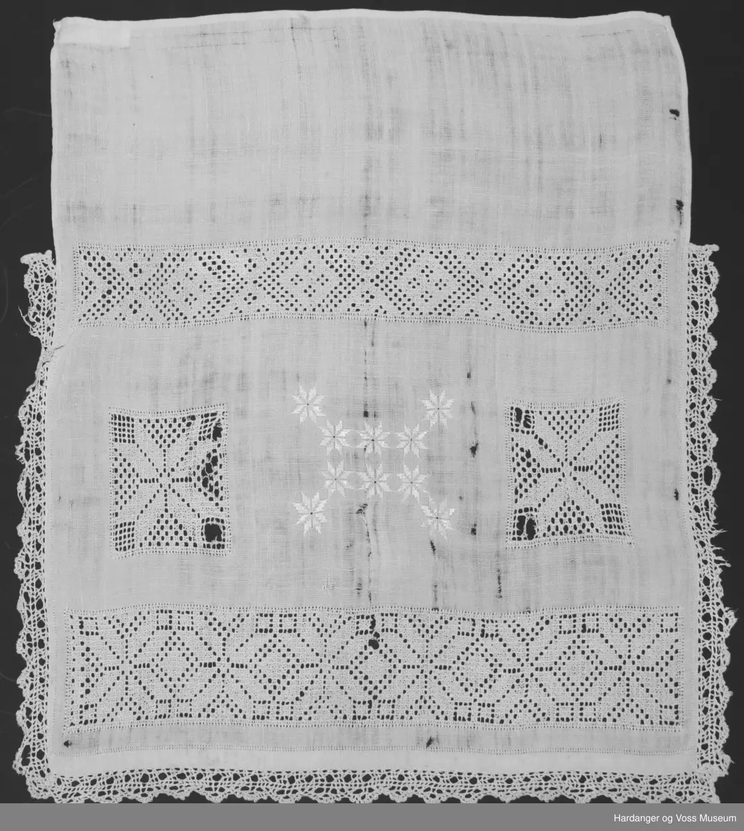 Over framstykket hekla blonde påsydd langs kanten, åttebladspirer