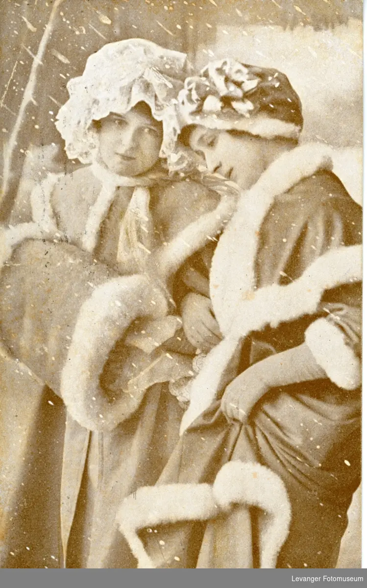 Postkort, julekort med to kvinner i muffer og vinterkåper.
