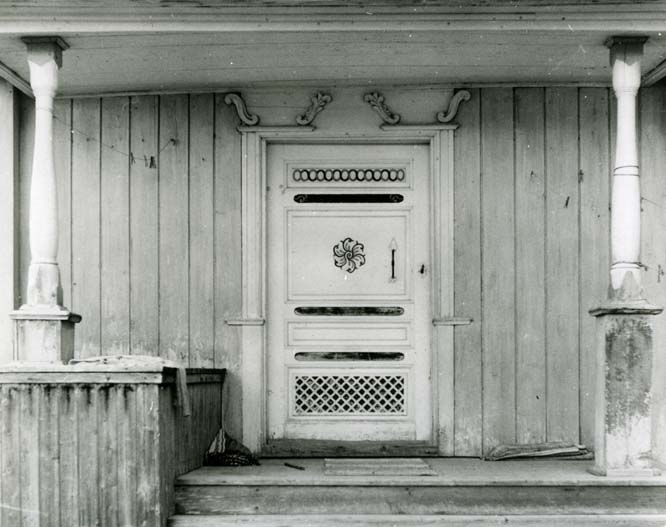 En veranda med svarvade kolonner och bemålad dörr i Bergsjö.