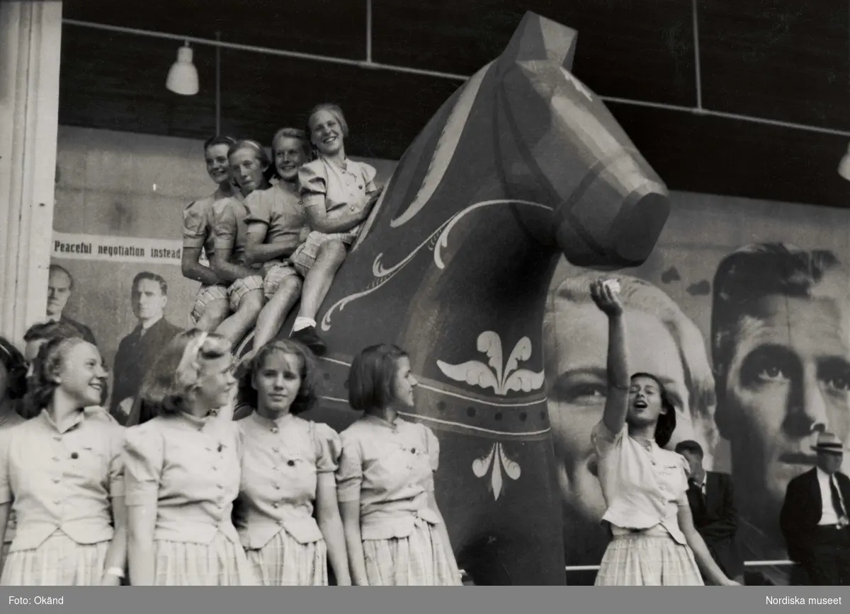 Fyra flickor sitter på en stor dalahäst vid svenska paviljongen på världsutställningen i New York 1939