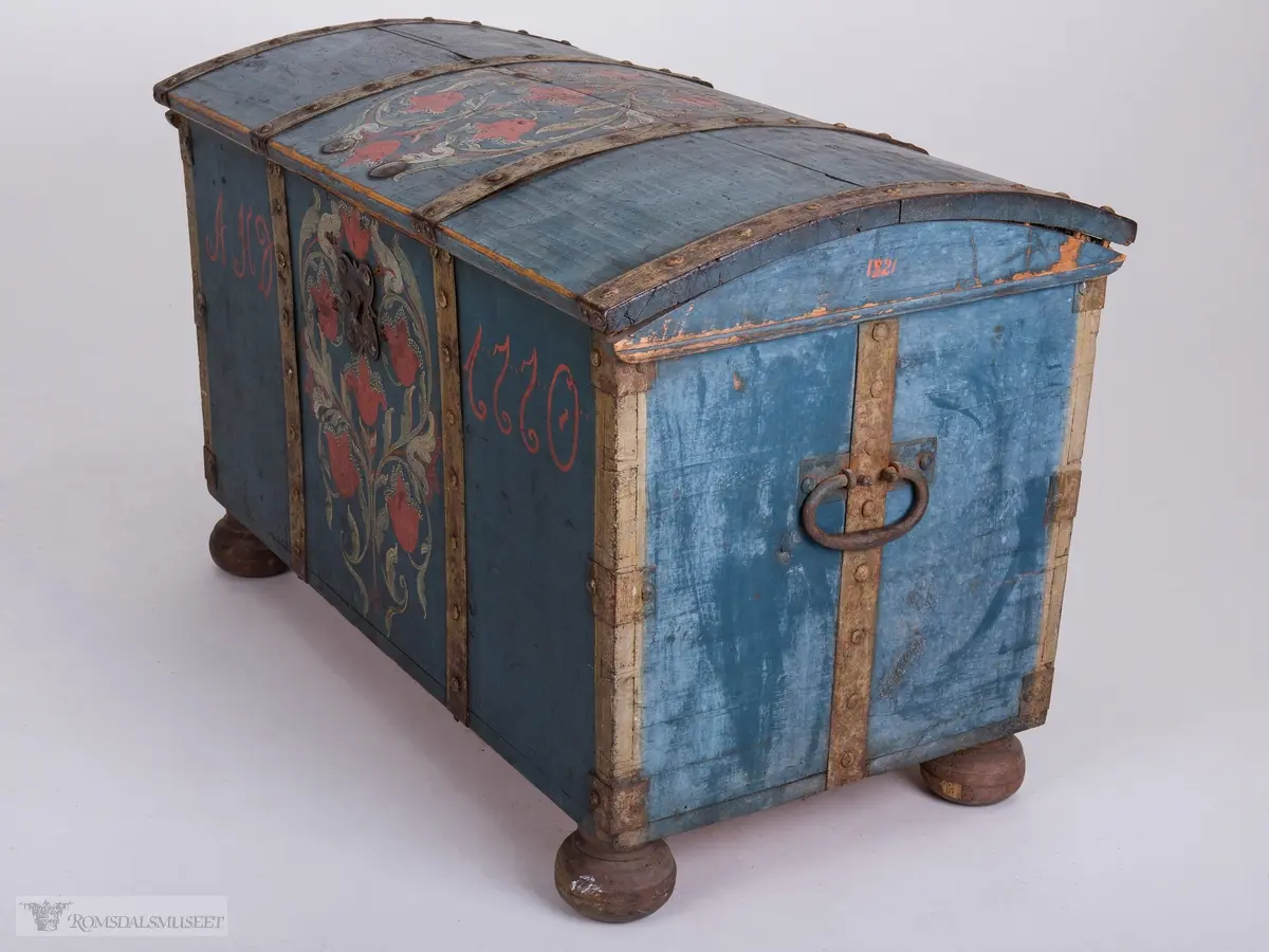 Rosemaling på blå bunn.  Det midtre feltet er dekorert med symetrisk rosemaling på blå bunn . I de to andre feltene på fronten er malt med initialene.