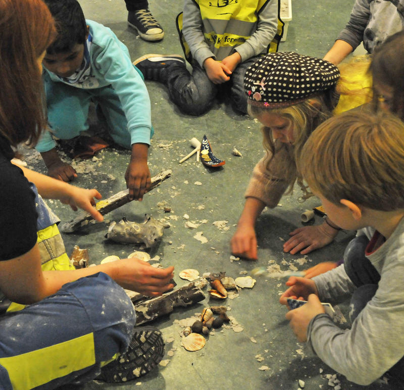 Barn sitter i sirkel, leker arkeologer, graver ut funn fra sandkasser. (Foto/Photo)