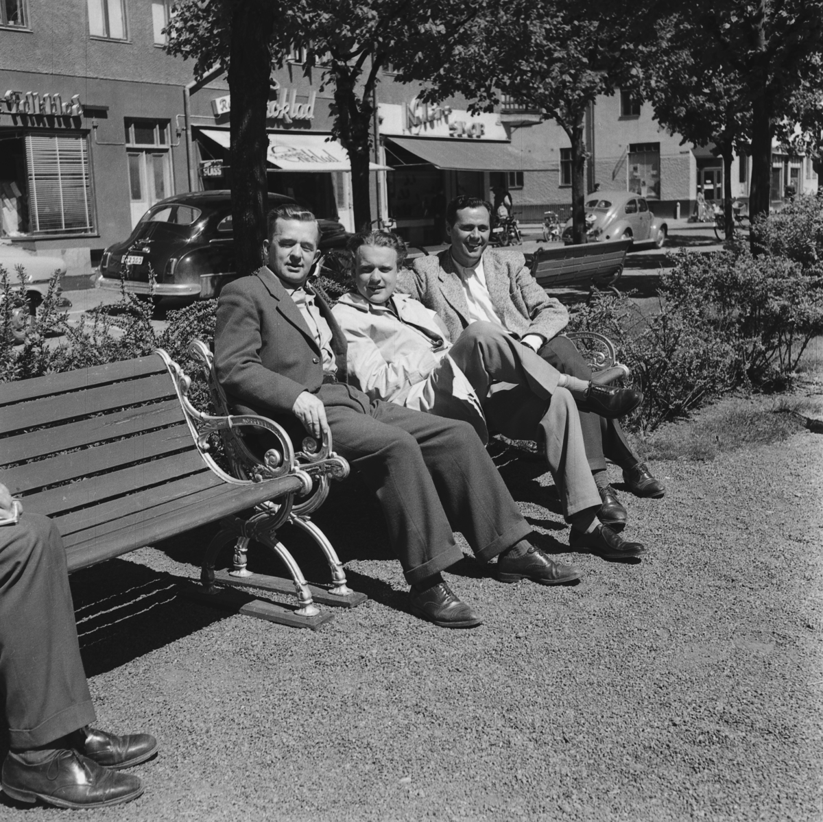 Tre herrar Jakobsson, Sandberg och Bohm sitter på en parkbänk på Esplanaden i Huskvarna.