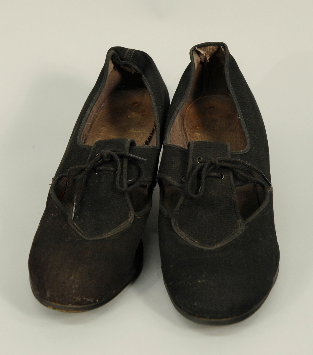 Skoene av pløse med fire snørehull og tvinnet trådlisser. Foret innvendig med grå bomullsgabardin. Heleskoen er foret også sålen.