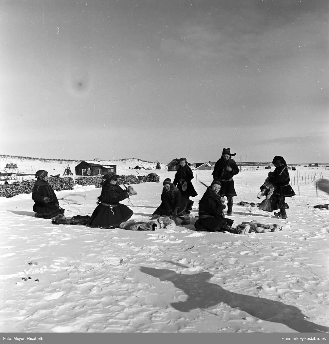Utenfor Kautokeino skoleinternat. Skolebarna banker dorkene i snøen. Fotografert påsketider 1940.