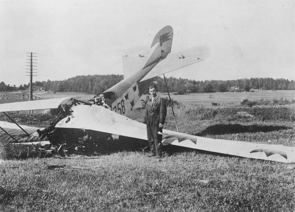 Ett havererat flygplan Albatros NAB 9 nummer 758 tillhörande Flygkompaniet ligger på ett fält. En man står bredvid.