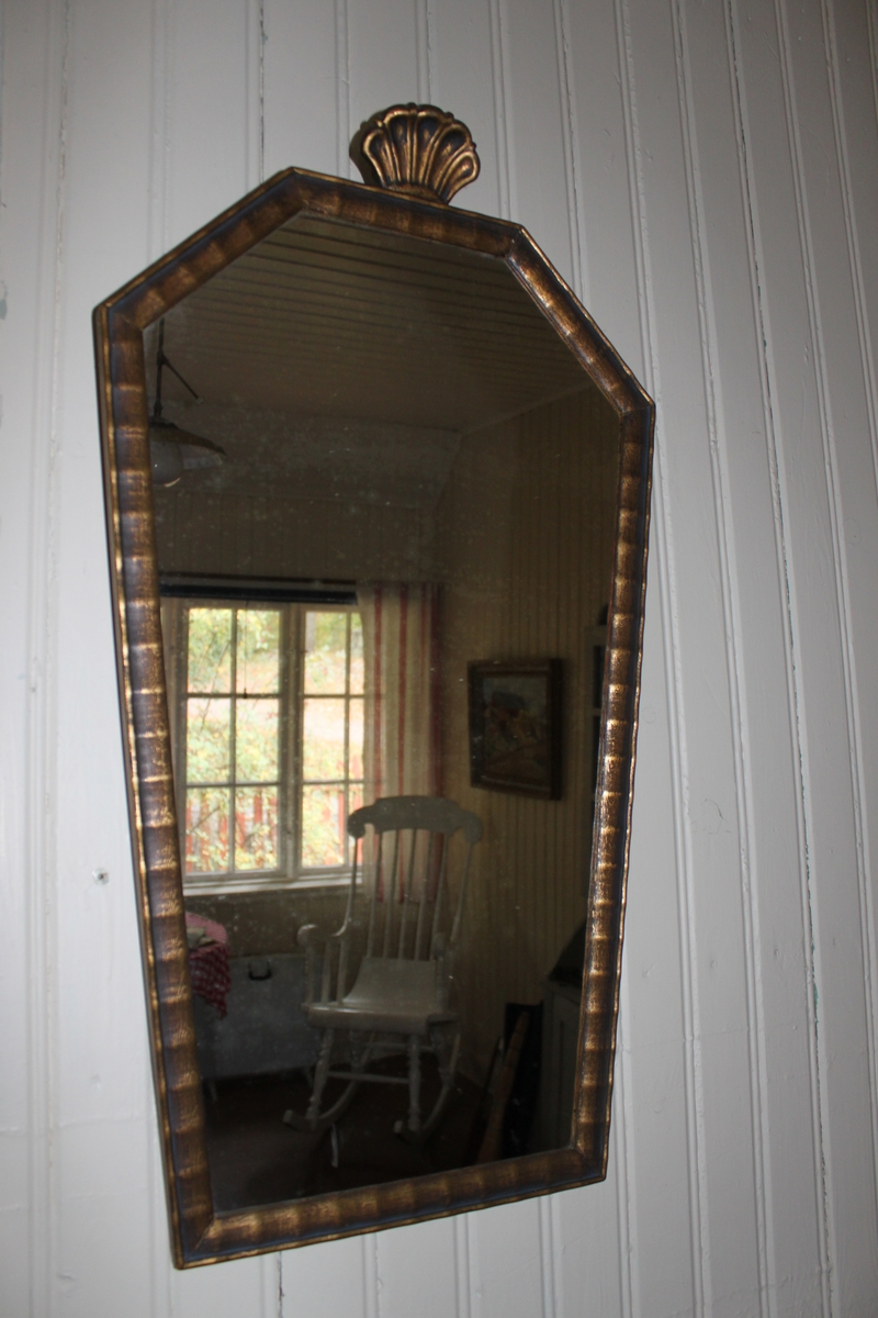 Förgylld spegel med träram för väggmontage. Detalj i form av en stiliserad snäcka i trä.