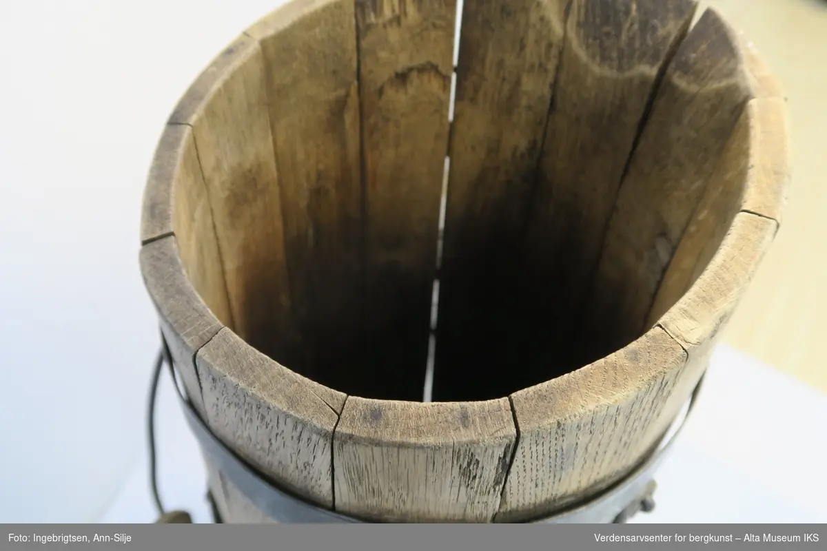 Sylinderformet trespann med hank. Spannen er smalere på toppen og der skrår kanten opp til den ene siden.